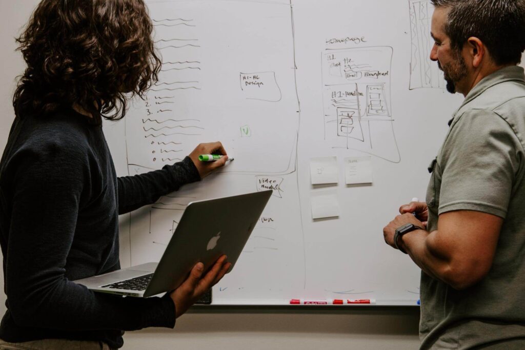 Two men discussing the website structure in a whiteboard